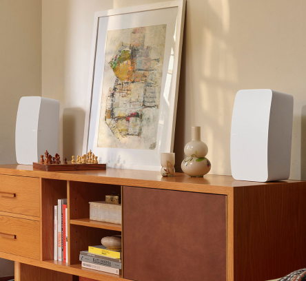 Two white speakers on a wood desk