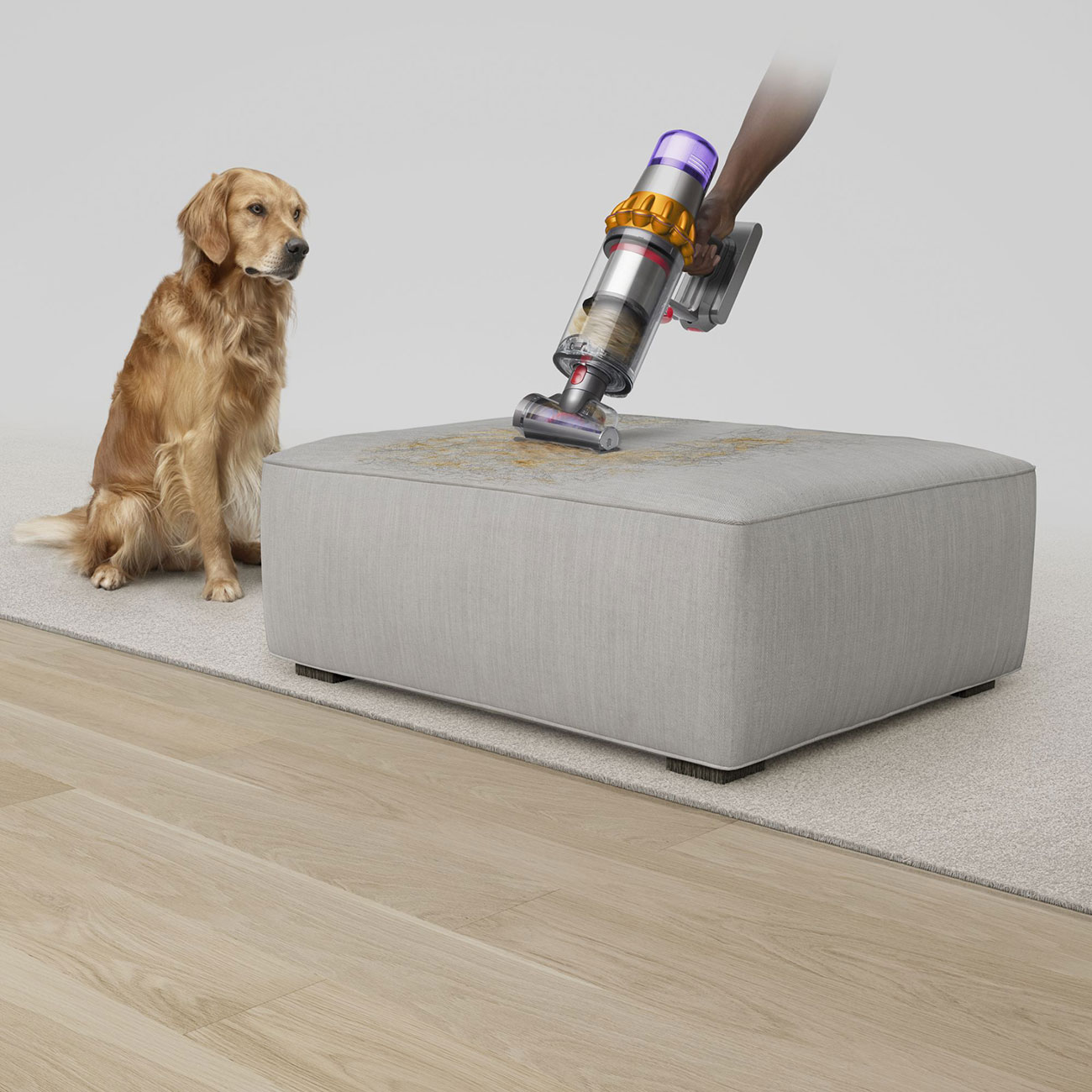 Dyson V15 Cordless Handheld Vacuum Used by a Person to Clean Pet Dander on an Ottoman
