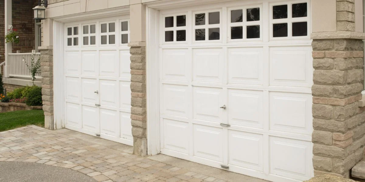 A white garage door with silver hardware and box windows along the top.