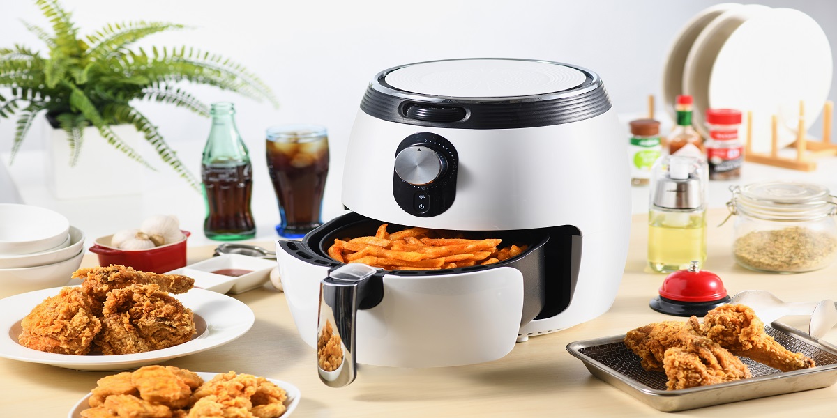 White air fryer with french fries inside sitting on a counter