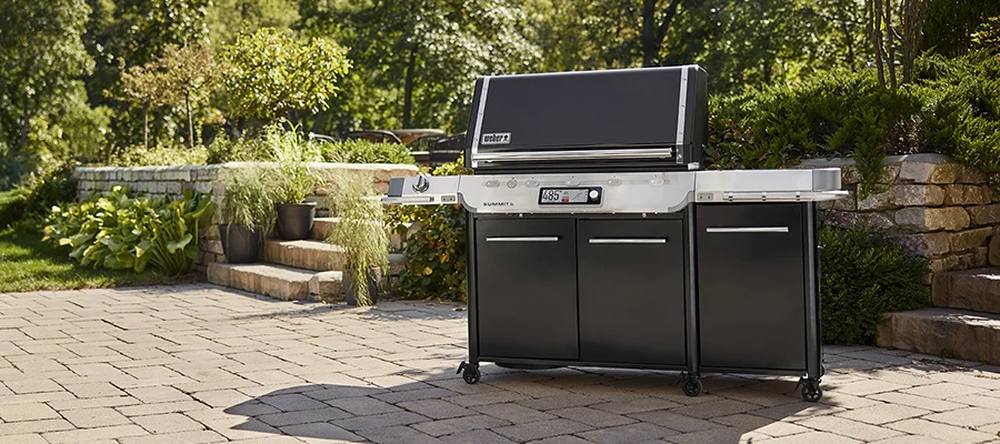 A black Weber Summit Smart grill sitting on a stone patio in a backyard