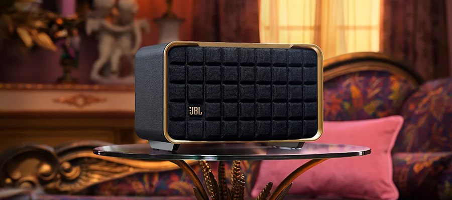 The JBL Authentics 200 speaker sitting on a glass table in a lavish magenta room
