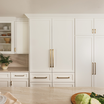 Front view of a Thermador refrigerator with white double doors and gold handles, built into surrounding cabinetry.