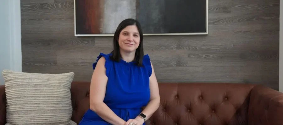 Beth Shapiro on a leather couch beside a pillow and in front of an abstract painting