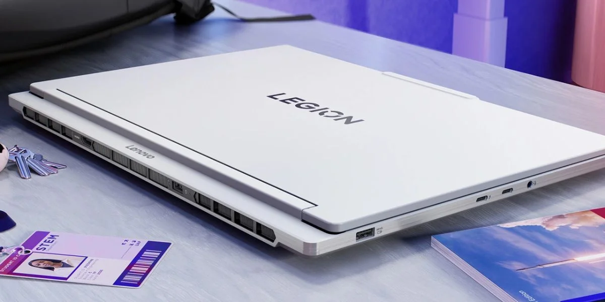 A white gaming laptop on the desk beside a STEM work ID tag, set of keys and a book