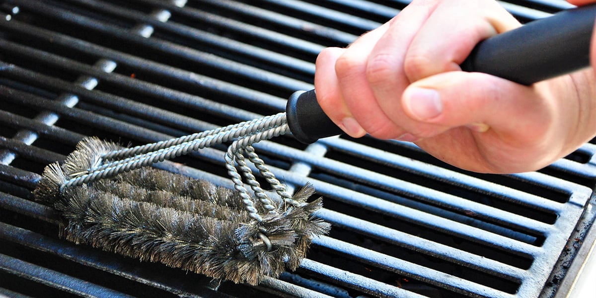 Hand brushing a grate with a grill brush