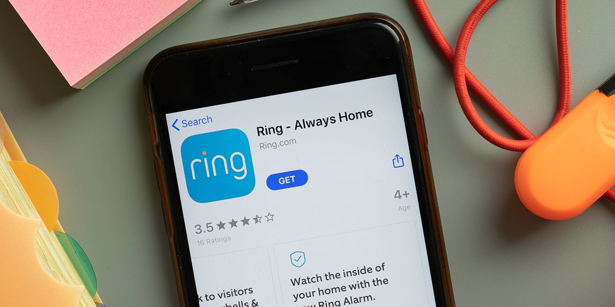 A smart phone with its screen illuminated to the Ring app on the App Store page