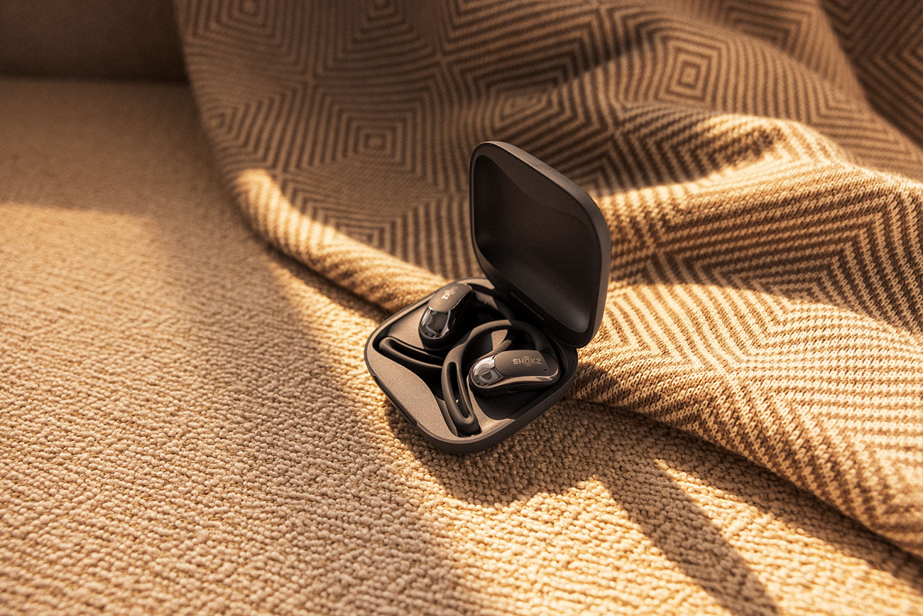 Top View of Shoks Open-Ear Earbuds and Case on Couch