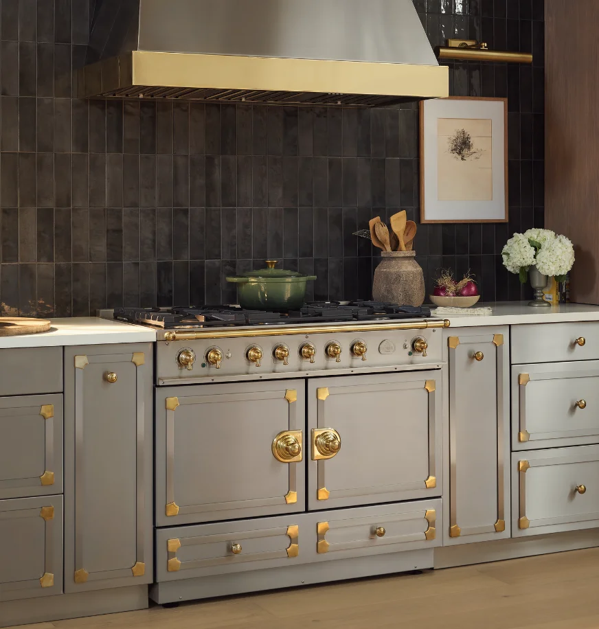 Taupe La Cornue range with brass hardware in a kitchen with dark charcoal tile backsplash