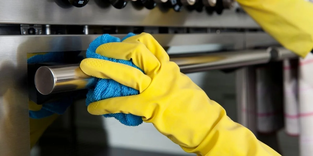 A person cleaning a stainless steel range.