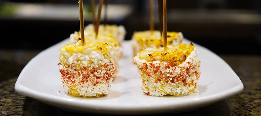 Small corn on the cob skewers with cheese and other elote toppings
