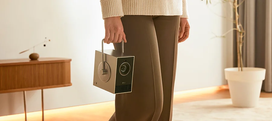 A woman holding the LG CineBeam Q projector by the carrying handle