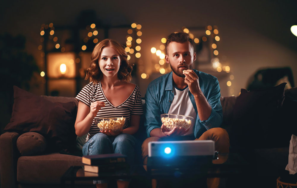 Two people watching TV with popcorn
