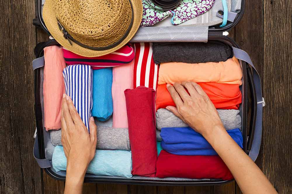 Person placing clothes into a travel suitcase