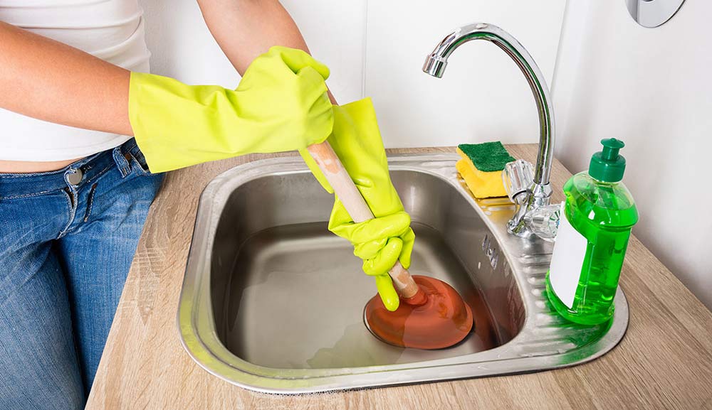 Person Using a Plunger to Unclog a Sink Drain