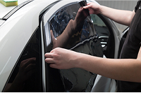 Technician applying window tint film to a car window