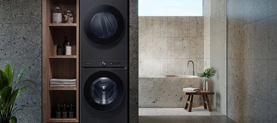 A black stacked washer-dryer unit installed within a tiled bathroom
