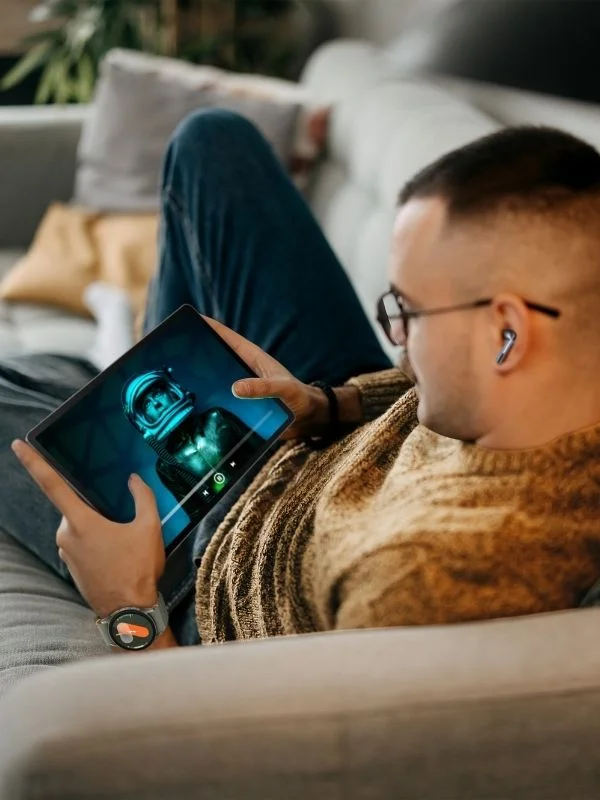 A person sitting on the couch watching a movie on a samsung galaxy tab