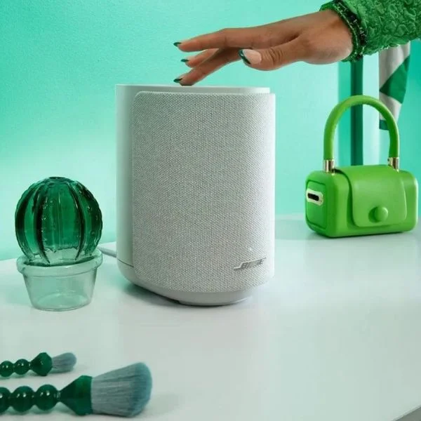 A person pressing a button on the top of a white Bose Lifestyle Ultra speaker.