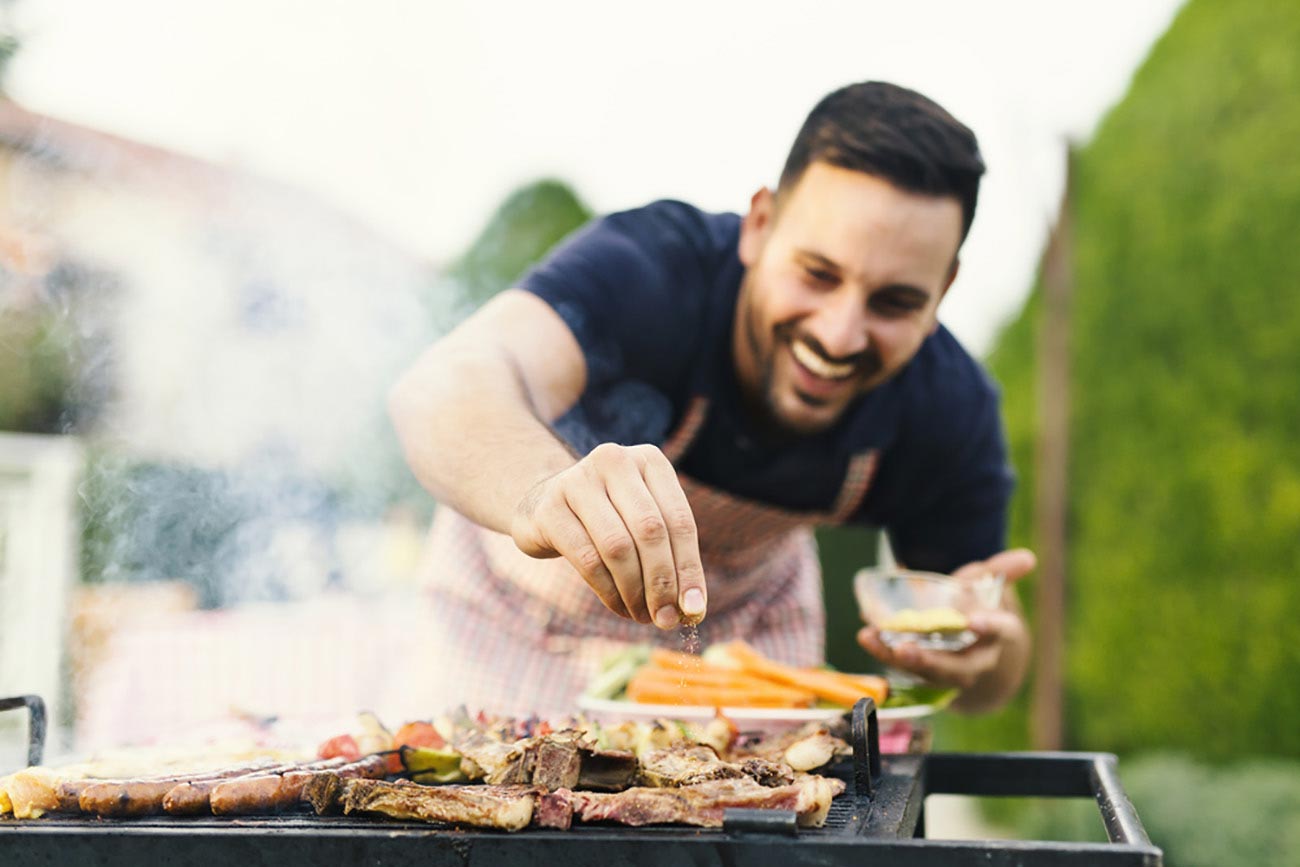 Man Seasoning Meat on Gas Grill