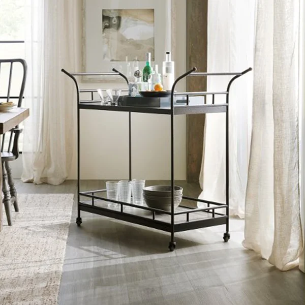 A black bar cart full of glasses and liquors.