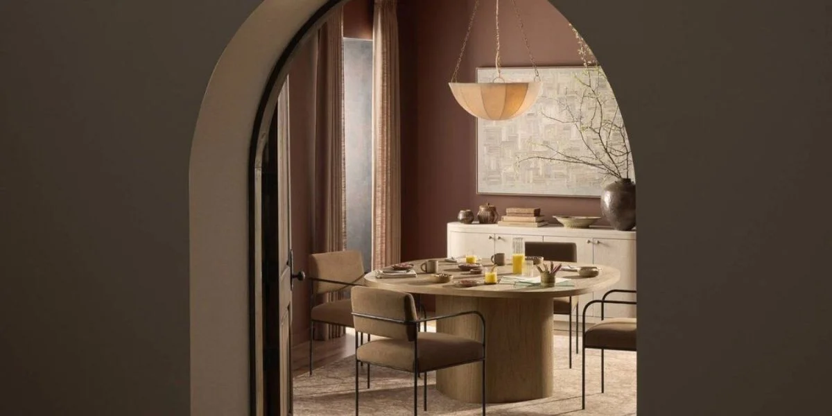 A round dining room table with four chairs seen through a doorway