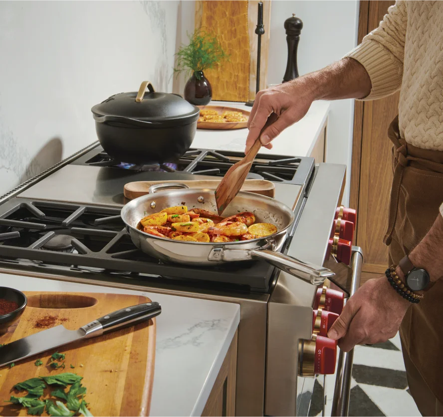 A person expertly prepares food on a Wolf range, highlighting the precision and control of the stove top