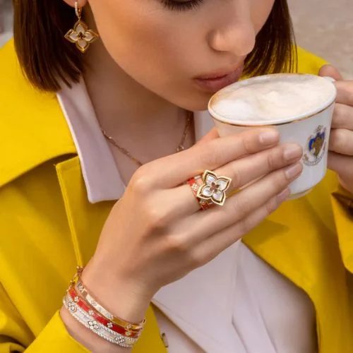 Tight shot on a person drinking coffee with a Roberto Coin Floral ring and additional Roberto Coin Rings