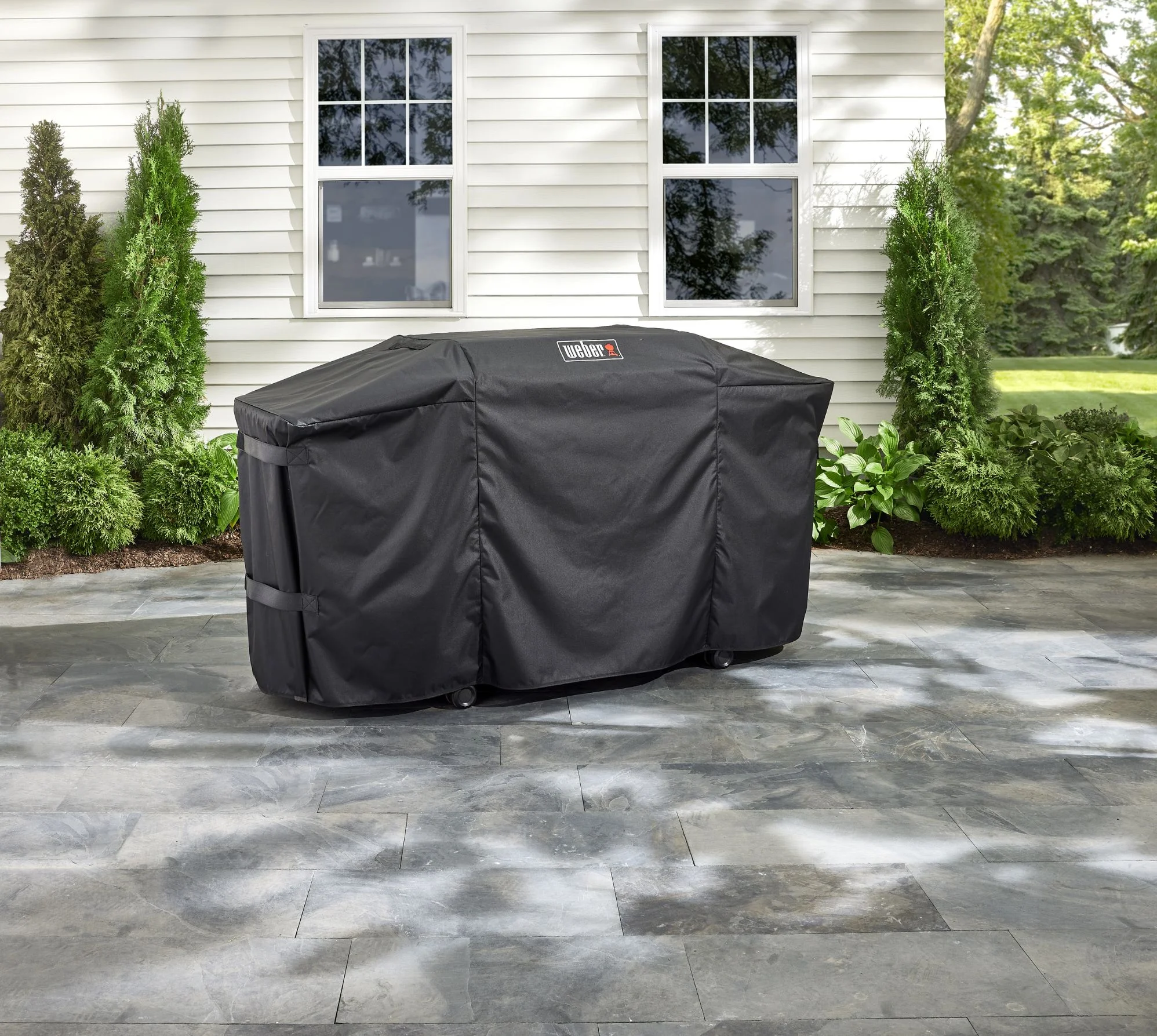 A wide bright shot of a weber grill that is covered in a nice backyard showcasing the perfect fit of a weber grill cover