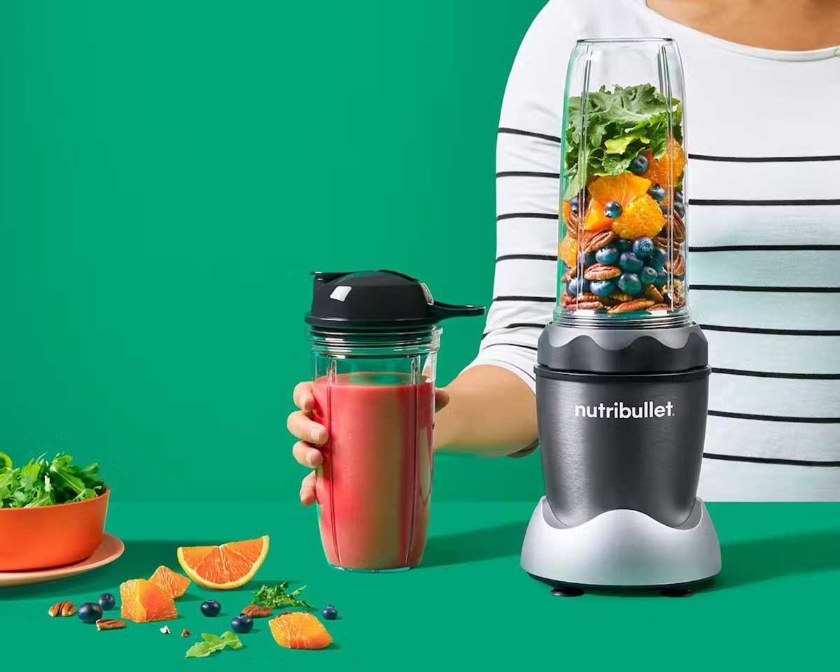 A Woman Holding a Full Smoothie Made from a Gray NutriBullet Pro 1000 Personal Blender
