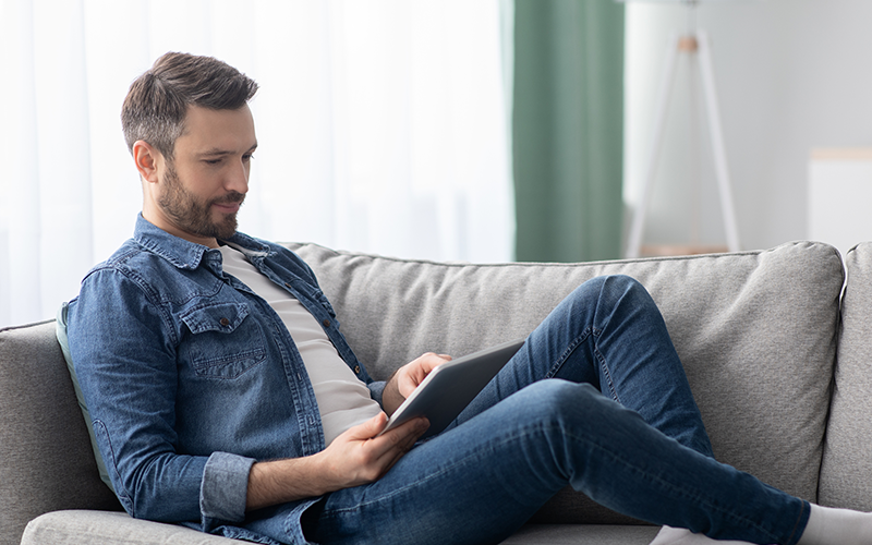 person sitting on the couch lounging while browsing a tablet