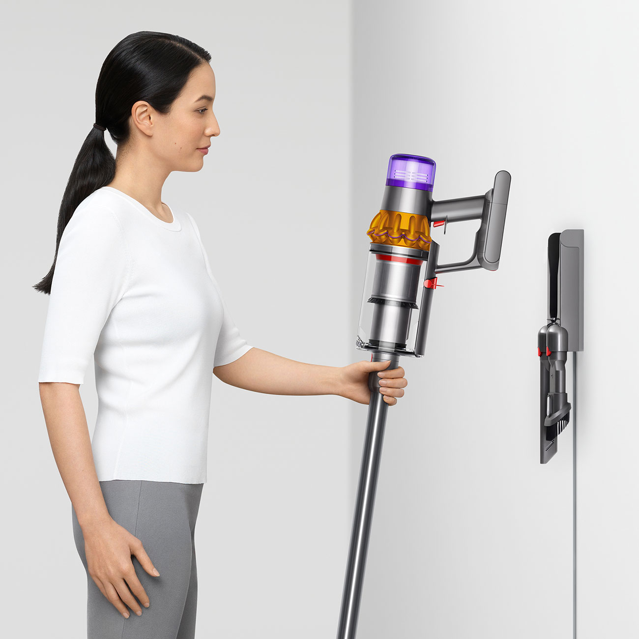 Dyson V15 Cordless Handheld Vacuum in the Left Hand of a Woman Placing Vacuum into Wall Charger
