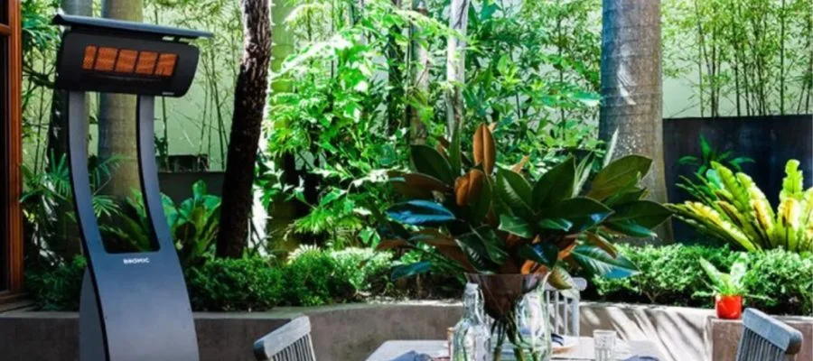 A tall electric heater on a patio beside a dining table and chairs