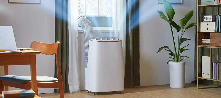 A portable air conditioner sitting in front of a living room window releasing cool air it's pulling from outside