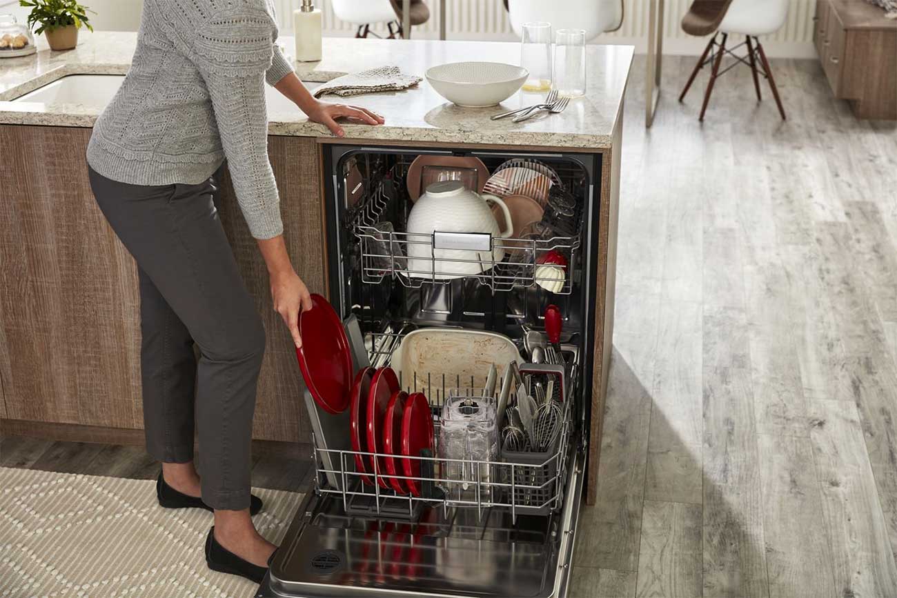 Woman Loading Dishes in a 24 Inch Stainless Steel KitchenAid Dishwasher