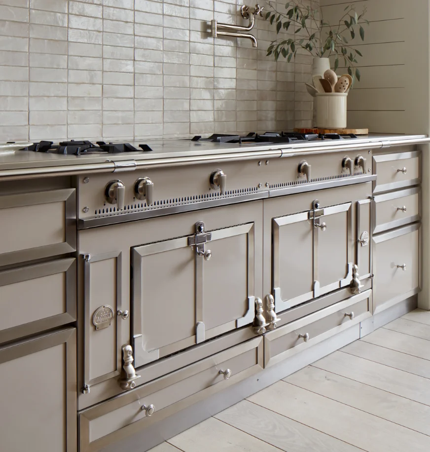 Taupe La Cornue range in a kitchen with cream subway tile backsplash and a wall-mounted pot filler