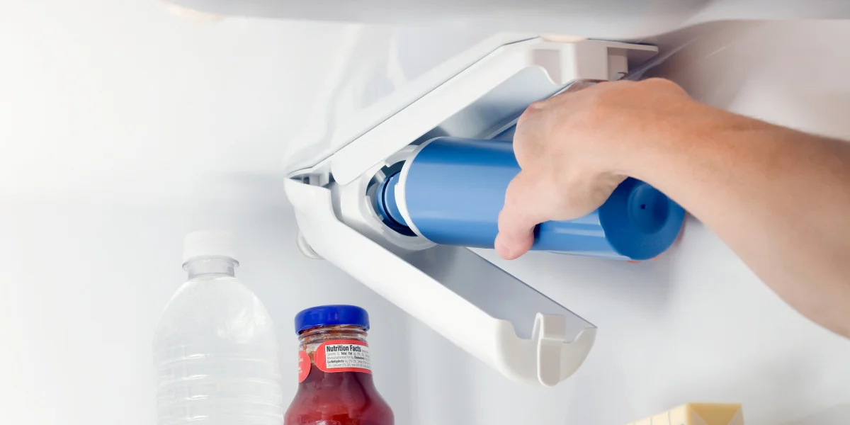 hand changing water filter inside a white refrigerator