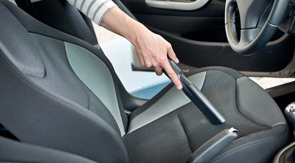 Person cleaning car with vacuum hose