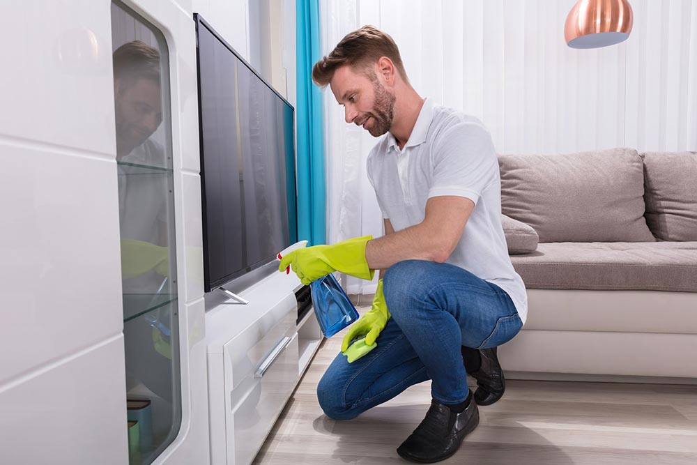Person suing cleaning spray on a TV screen