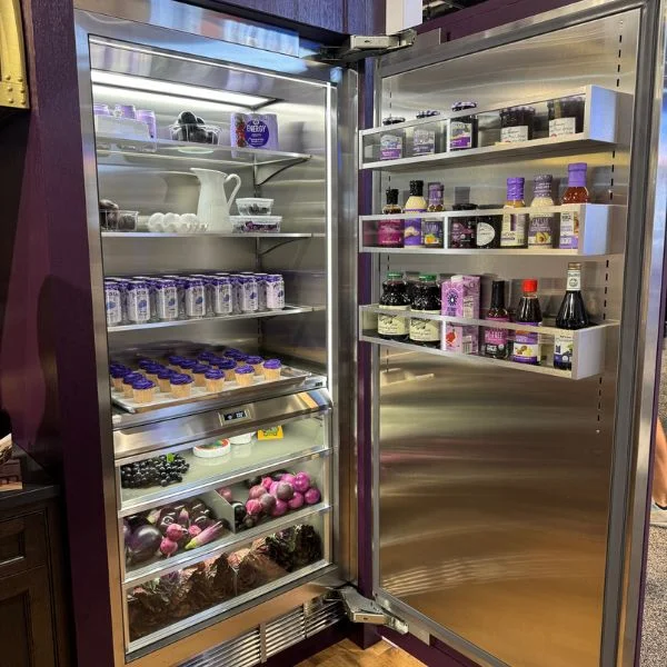 A fully open BlueStar built-in refrigerator in Purple Violet, with all purple foods and drinks inside.