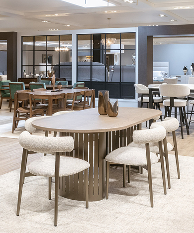 Elegant dining room furniture display with round table and upholstered chairs.