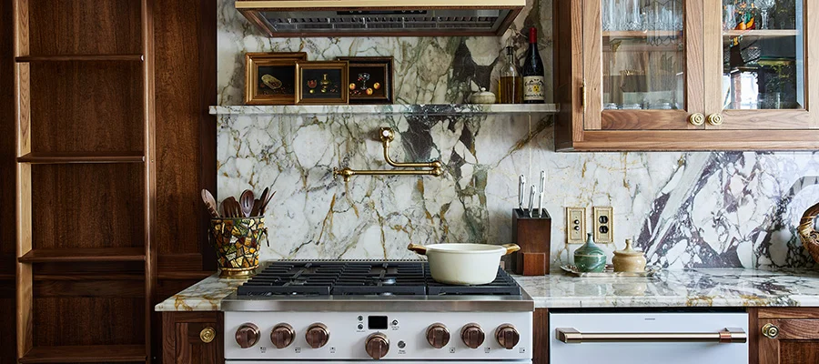 matte white gas range and dishwasher in kitchen with dark wood cabinets and veined marble counters and backsplash