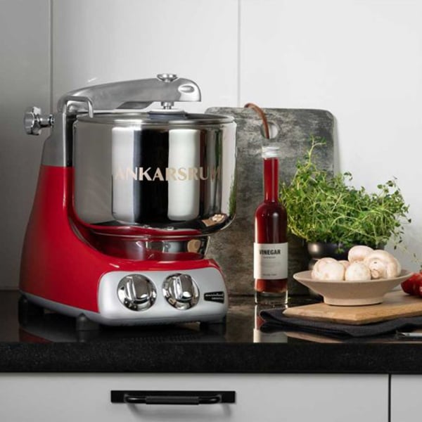 A red and silver stand mixer sitting on a countertop next to cooking ingredients.