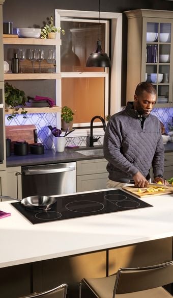 a person preparing food on the counter about to cook on the pan on the ge profile induction cooktop