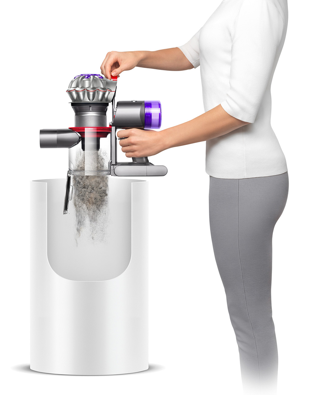 Woman in Grey Pants Emptying the Dust Bin of a Dyson V8 Cordless Stick Vacuum
