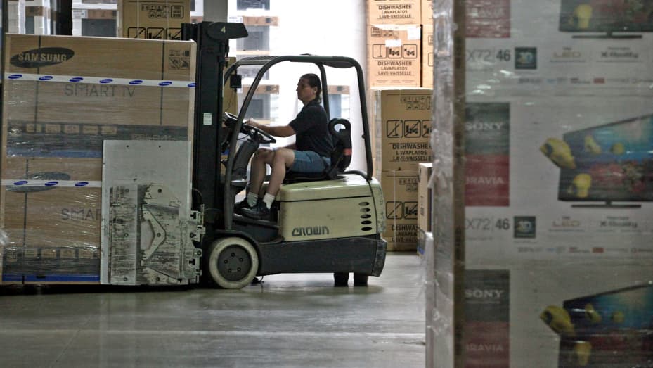 An employee using a forklift in the warehouse to transport Smart TVs