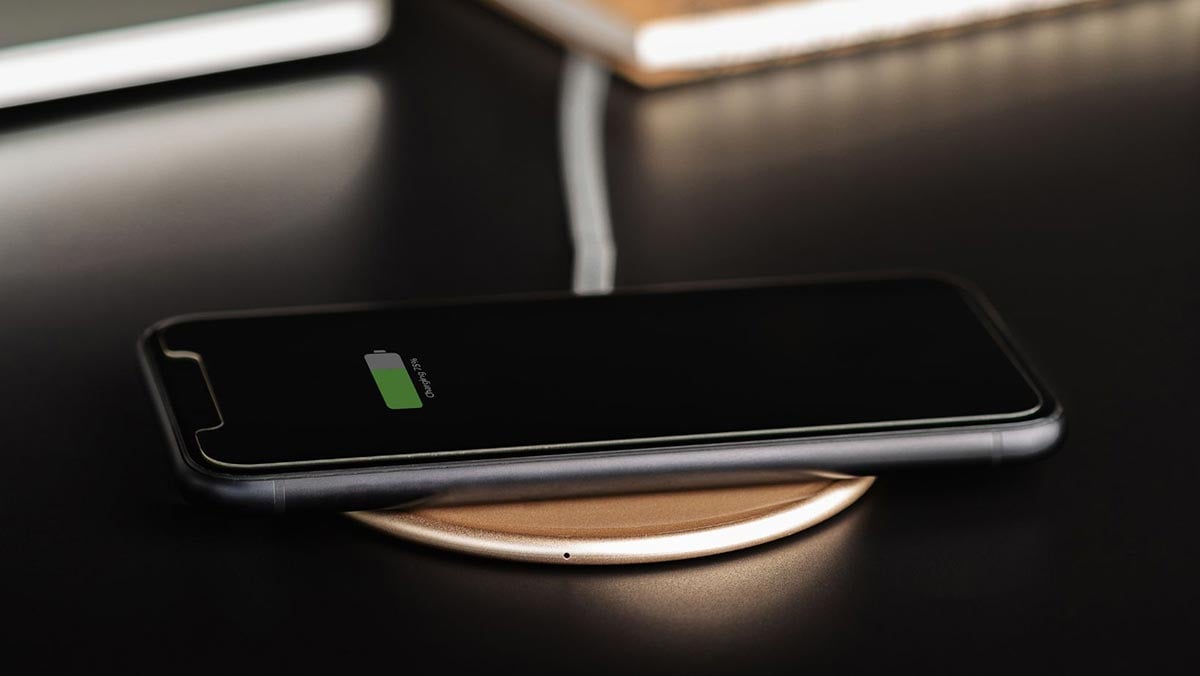 Black iPhone sits on a round wireless charger