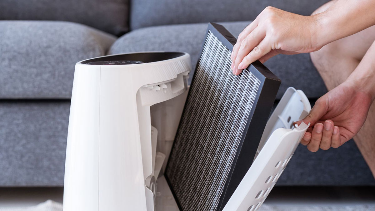 Close-up of a hand removing a filter from a white air purifier