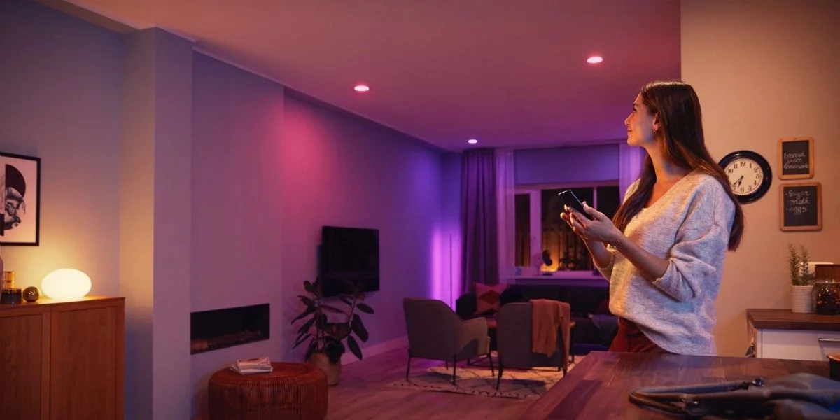 A woman adjusting the colorful smart lighting in her room, showcasing warm colors and pink and purple effects