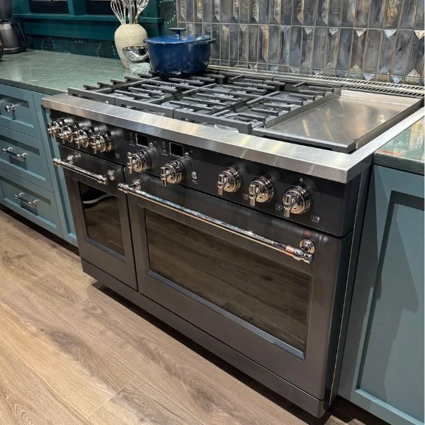 Matte black Cafe range with nickel hardware in a kitchen with deep teal cabinets.